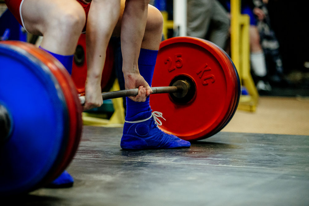 Weibliche Powerlifting Athletin macht Sumo Kreuzheben mit Langhantel